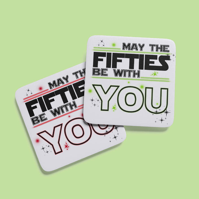 Two white coasters with a red and green design featuring the text May the Fifties Be With You.