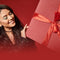 A woman holding a red gift box with a dark red ribbon against a red background.