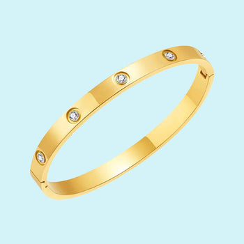 A sleek gold bracelet with a smooth finish, featuring evenly spaced round diamond accents. The bracelet is set against a light blue background, highlighting its elegant and luxurious design.