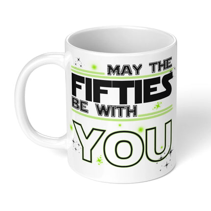 White ceramic mug with "MAY THE FIFTIES BE WITH YOU" in black and green typography, decorated with stars - perfect 50th birthday gift