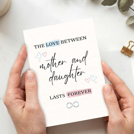 Personalised mother and daughter card with infinity symbol, pastel hearts, held in hands