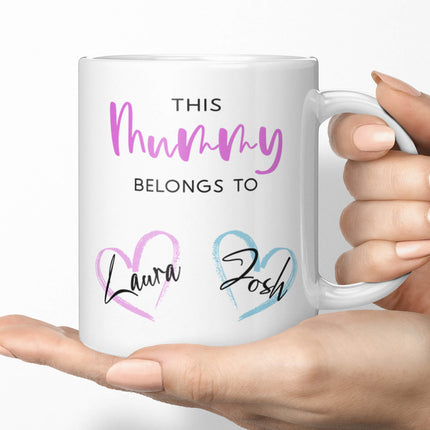 Hands holding an 11oz custom mummy mug displaying Laura and Josh in heart designs.