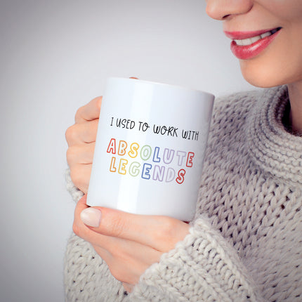 Person holding a mug with text 'I used to work with absolute legends' against a neutral background