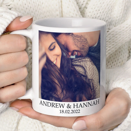 White mug with a printed photo of a couple and text held by a person against a white background