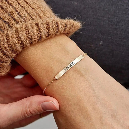A personalised bracelet worn by a woman, featuring a name engraved on it.