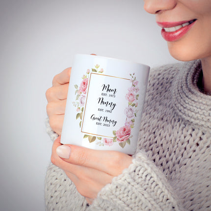 Woman holding a personalized floral mug with "Mum, Nanny, Great Nanny" and establishment years printed on it.