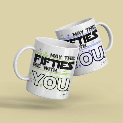Two ceramic mug with "MAY THE FIFTIES BE WITH YOU" in black and blue and black and green typography, decorated with stars - perfect 50th birthday gift